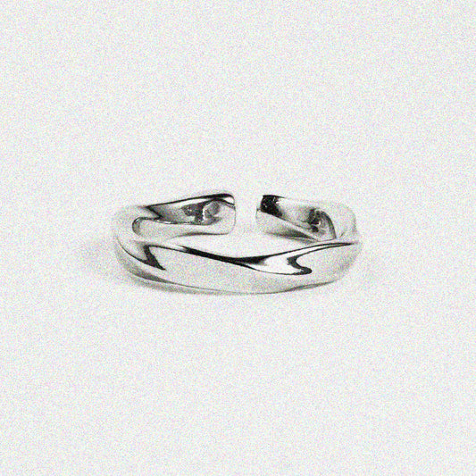  Silver band-style ring with a wavy design, displayed on a plain white surface.