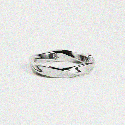 A smooth, twisted silver ring placed on a neutral background.