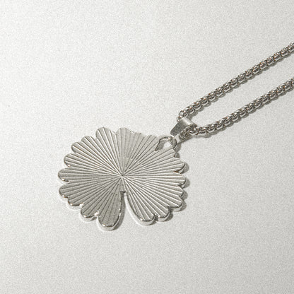 A silver necklace featuring a delicate leaf pendant, elegantly designed to enhance any outfit.
