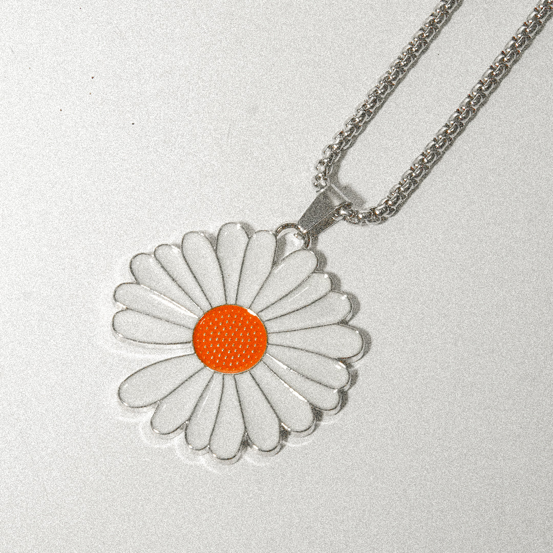 A delicate white and orange flower pendant elegantly hanging from a silver chain, showcasing its intricate design.