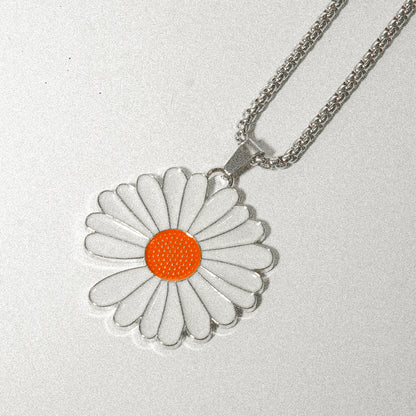 A delicate white and orange flower pendant elegantly hanging from a silver chain, showcasing its intricate design.