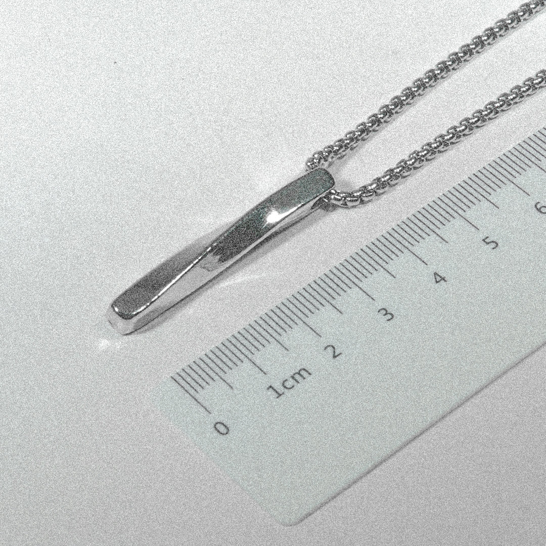 A silver necklace with a ruler resting on top, showcasing a unique blend of elegance and practicality.
