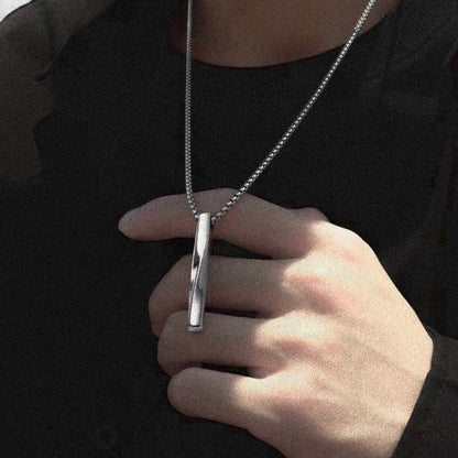 A man showcasing a stylish silver necklace featuring a sleek bar pendant.